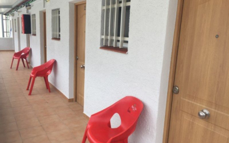 Fachada con puertas de acceso a las habitaciones con silla roja en la entrada